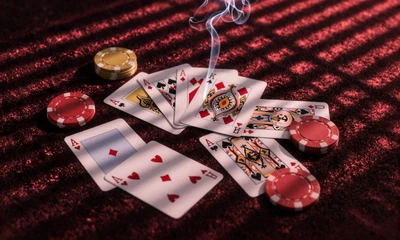 Verstreute Spielkarten und Casino-Chips auf schwarzem Samt mit Neon-Rot-Beleuchtung